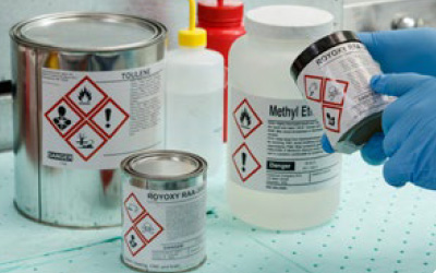 Chemik lepí štítok GHS na nádobu.